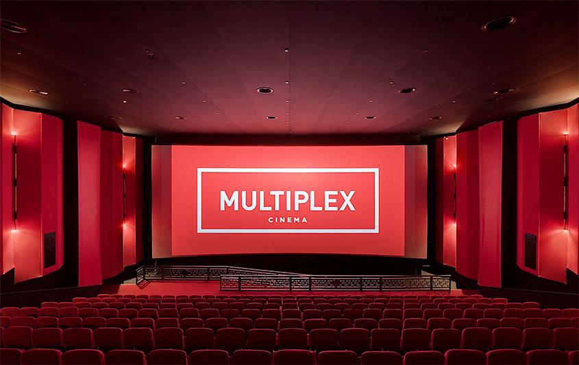 Spacious multiplex cinema with red seating and large screen displaying Multiplex Cinema in a modern theater setting.