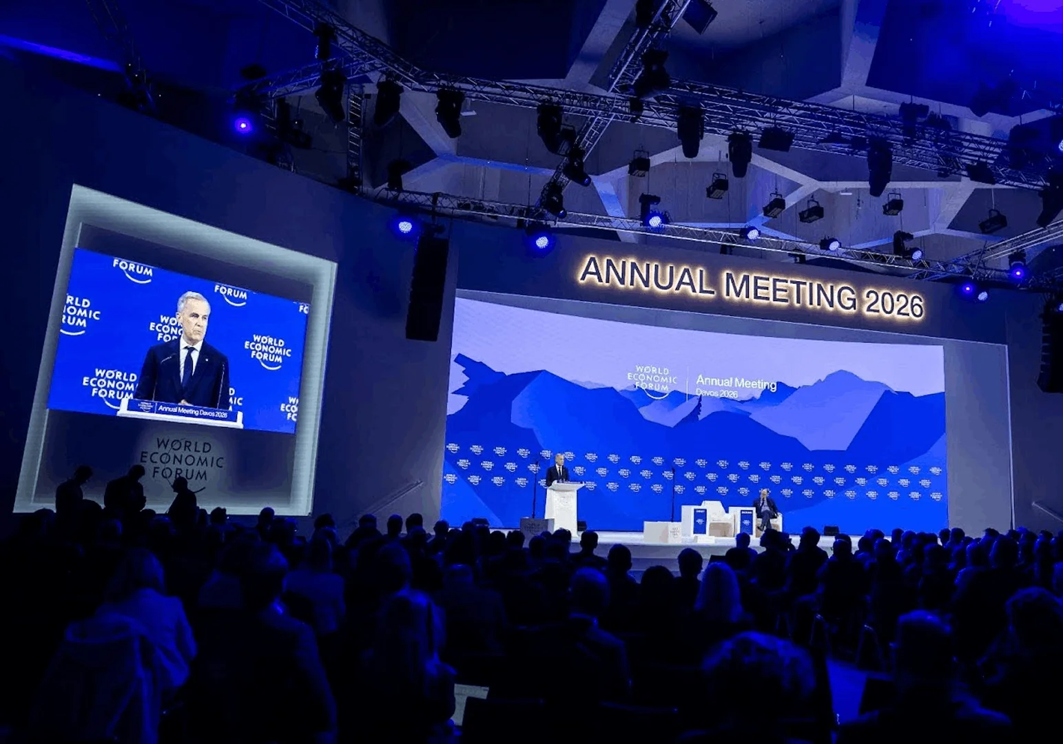 World Economic Forum Annual Meeting 2026 stage with speaker and audience in a dimly lit conference hall.